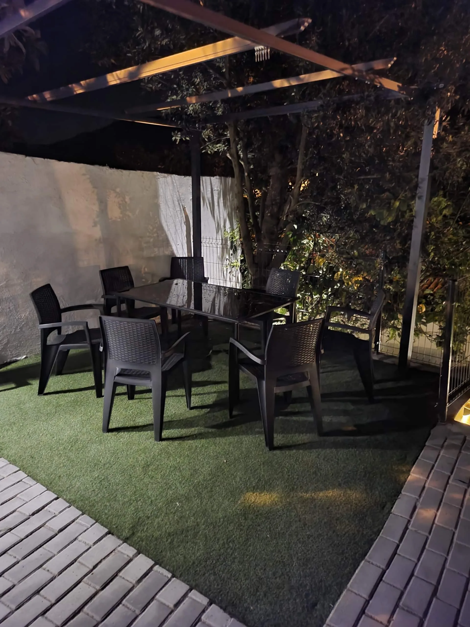 Mesa de jantar exterior sob pérgola iluminada